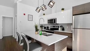 A modern kitchen with a central island, stainless steel appliances, and pendant lighting. - Luxury 2BR, 10ft ceiling, 5 mins from Dt (Edmonton)