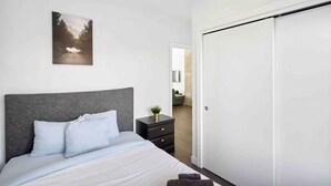 A bedroom with a bed, a nightstand, a painting, and a wardrobe. - Luxury 2BR, 10ft ceiling, 5 mins from Dt (Edmonton)