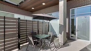 An outdoor patio with a table and chairs, a metal fence, and a glass door with the number 109. - Luxury 2BR, 10ft ceiling, 5 mins from Dt (Edmonton)