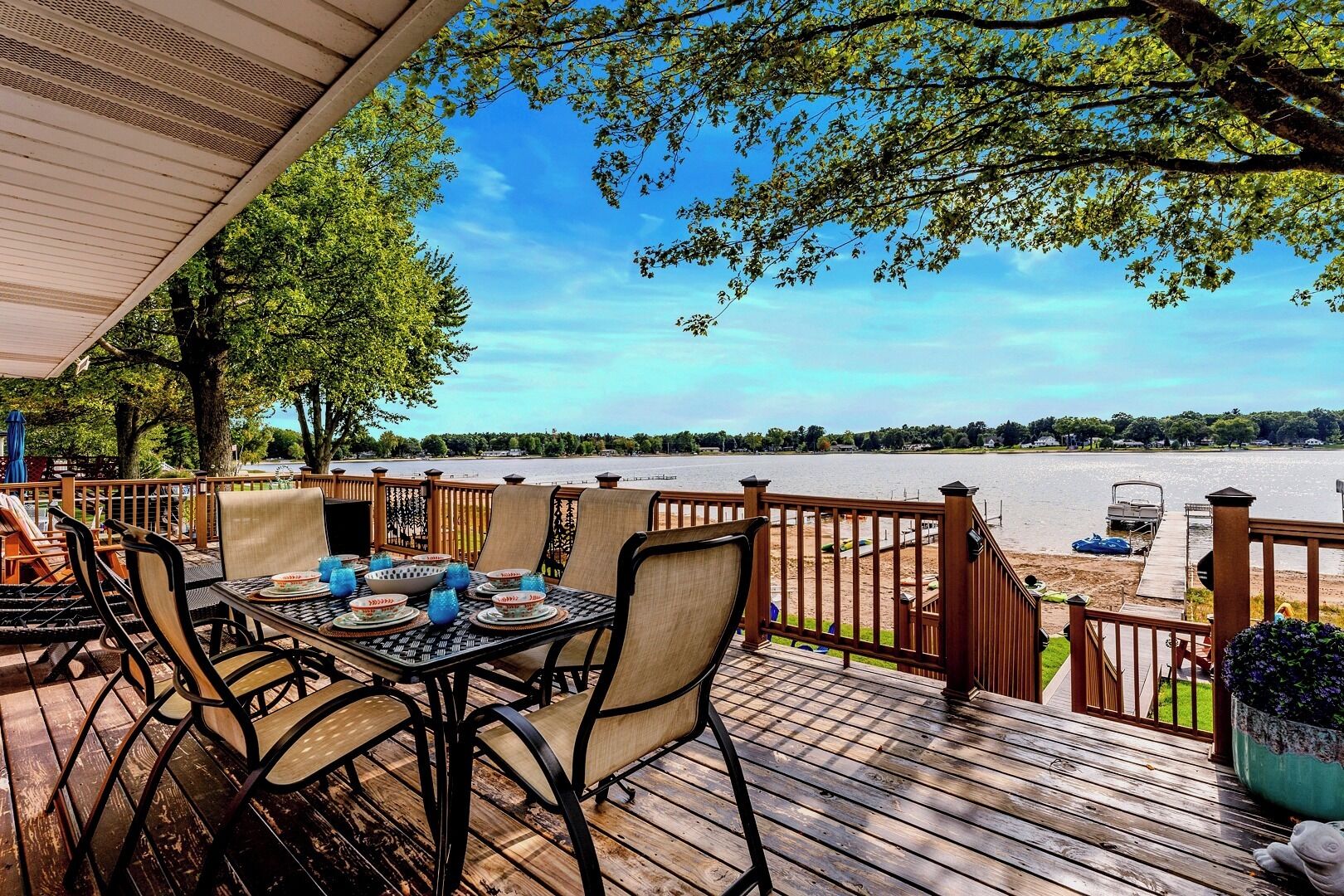 A wooden deck with a table set for dining, overlooking a body of water.