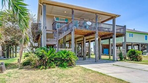 A two-story building with a balcony, a covered porch, and a visible address sign. - Easy Gulf-View Retreat w/ Big Deck, Outdoor Shower & Pet Friendly (Bolivar Peninsula)