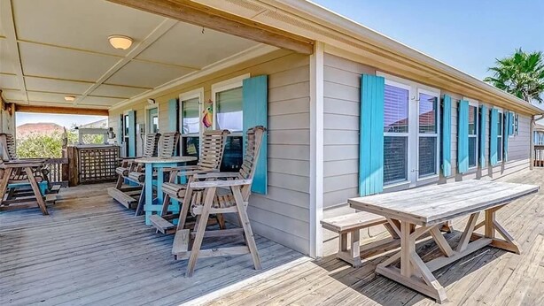 A covered outdoor deck with wooden furniture and a picnic table. - Easy Gulf-View Retreat w/ Big Deck, Outdoor Shower & Pet Friendly (Bolivar Peninsula)