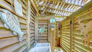 A wooden cabin with a small bathroom, a fish sculpture, and a sign indicating a price of $250. - Easy Gulf-View Retreat w/ Big Deck, Outdoor Shower & Pet Friendly (Bolivar Peninsula)