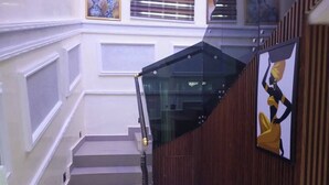 A staircase with a glass railing, wooden paneling, and a framed artwork on the wall. - 517VIP Suites and Apartments Awka (Awka)