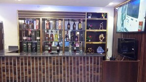 A bar area with shelves of liquor bottles, a television screen, and a wooden counter. - 517VIP Suites and Apartments Awka (Awka)