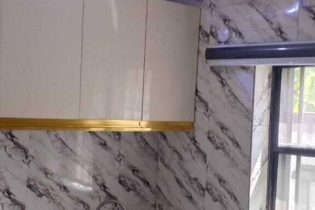 Una cocina con paredes de mármol, armarios blancos y un ventanal.