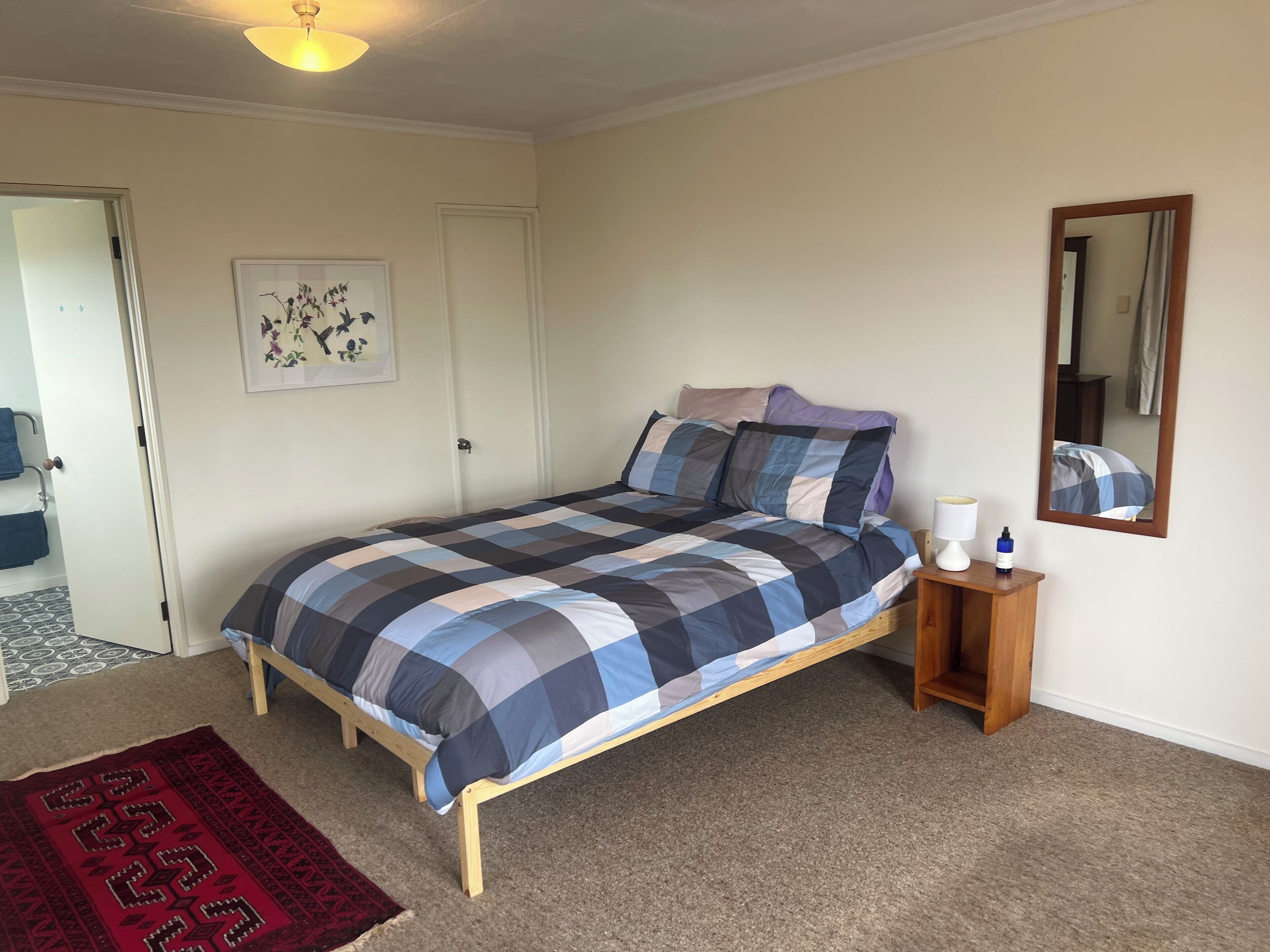 Une chambre à coucher avec un lit, une table de chevet, un miroir et une porte.