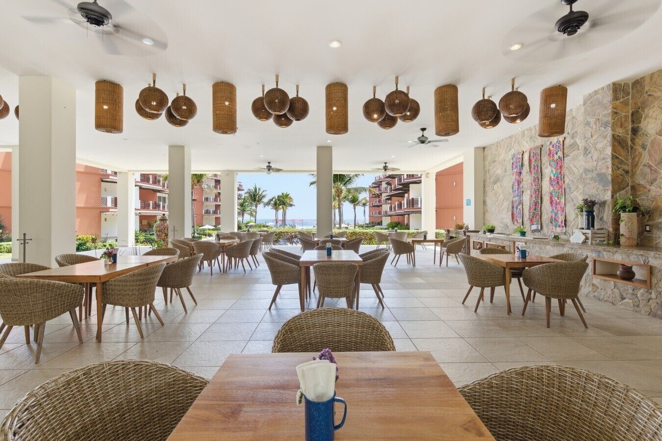A spacious outdoor dining area with wicker furniture and hanging light fixtures.