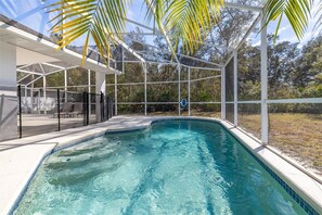 Ein Pool mit Glasumrandung, umgeben von einem weißen Zaun und Palmen.