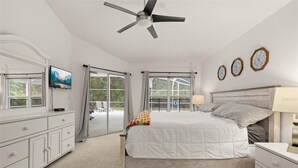 A bedroom with a bed, a nightstand, a dresser, a ceiling fan, and a TV on a dresser. - Cozy 4 Bedroom Home with South Facing Pool & 4 bedroom home (Davenport)