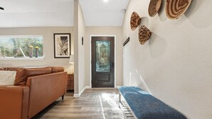 Un salon moderne avec un canapé en cuir marron, un banc bleu et un plancher en bois.
