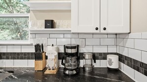 Une cuisine équipée d’une machine à café, d’un bloc à couteaux et d’une tasse posée sur le comptoir.