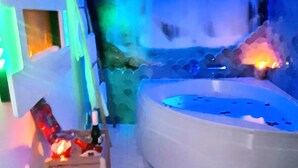 A spa area with a hot tub, a wooden chair, and a wall-mounted shelf with bottles. - Almoguer Rural Complex (Frailes)
