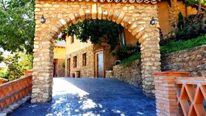 A stone archway leading to a building with a tiled roof and a door. - Almoguer Rural Complex (Frailes)