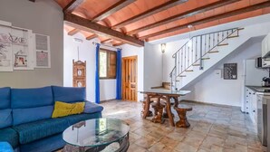 A living room with a blue sofa, a glass coffee table, and a wooden dining table. A staircase leads to the upper floor. - Almoguer Rural Complex (Frailes)