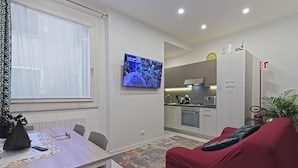 A modern apartment with a dining area, a living room with a red sofa, a kitchen, and a TV mounted on the wall. - Paint Venice House (Venezia)