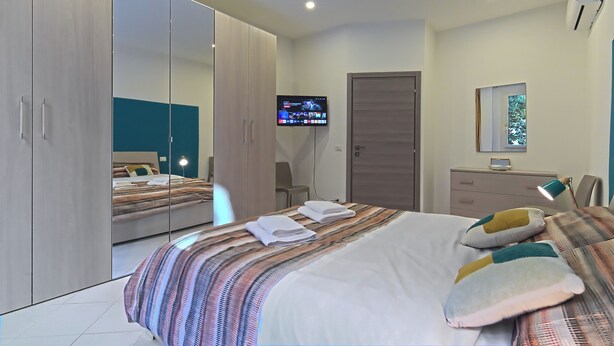 A modern hotel room with a large bed, a wardrobe, a television, and a desk. - Paint Venice House (Venezia)