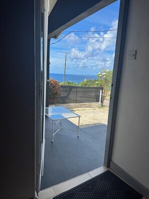A room with a sliding glass door leading to a balcony with a view of the ocean. - Cozy 2-bedroom house in tranquil West Terrace with AC (West Terrace)