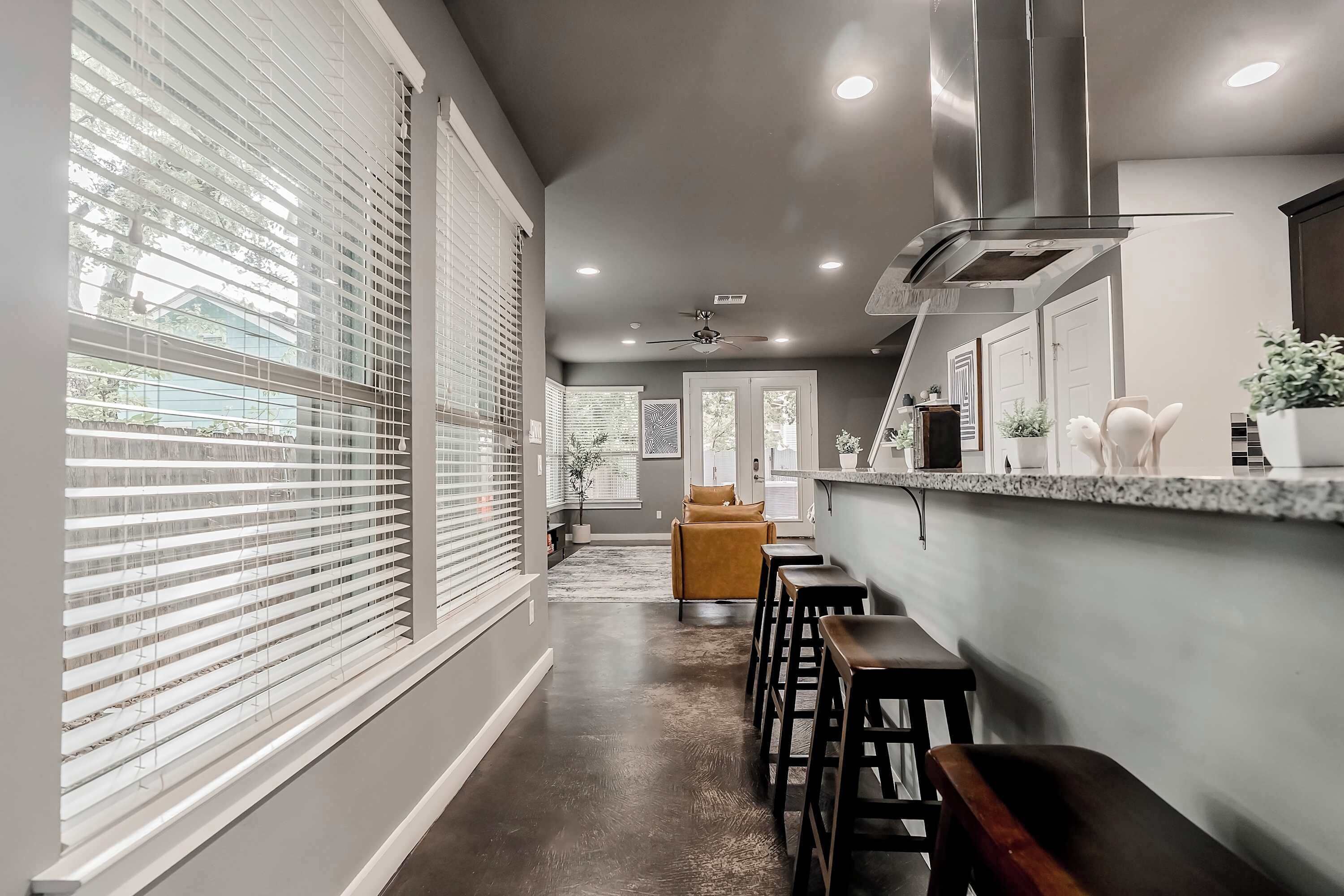 Una cocina moderna con una isla central, taburetes de bar y vistas al exterior a través de grandes ventanales.