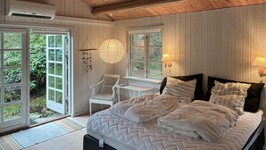 Un dormitorio con una cama grande, una silla, un ventanal y una lámpara colgante.