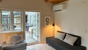 Una habitación acogedora con un sofá gris, techo de madera y un ventanal con vistas al exterior.