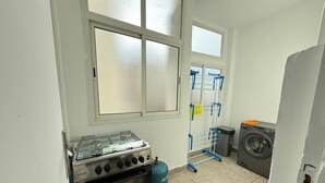 Une cuisine compacte équipée d’une cuisinière à gaz, d’un four et d’un lave-linge.
