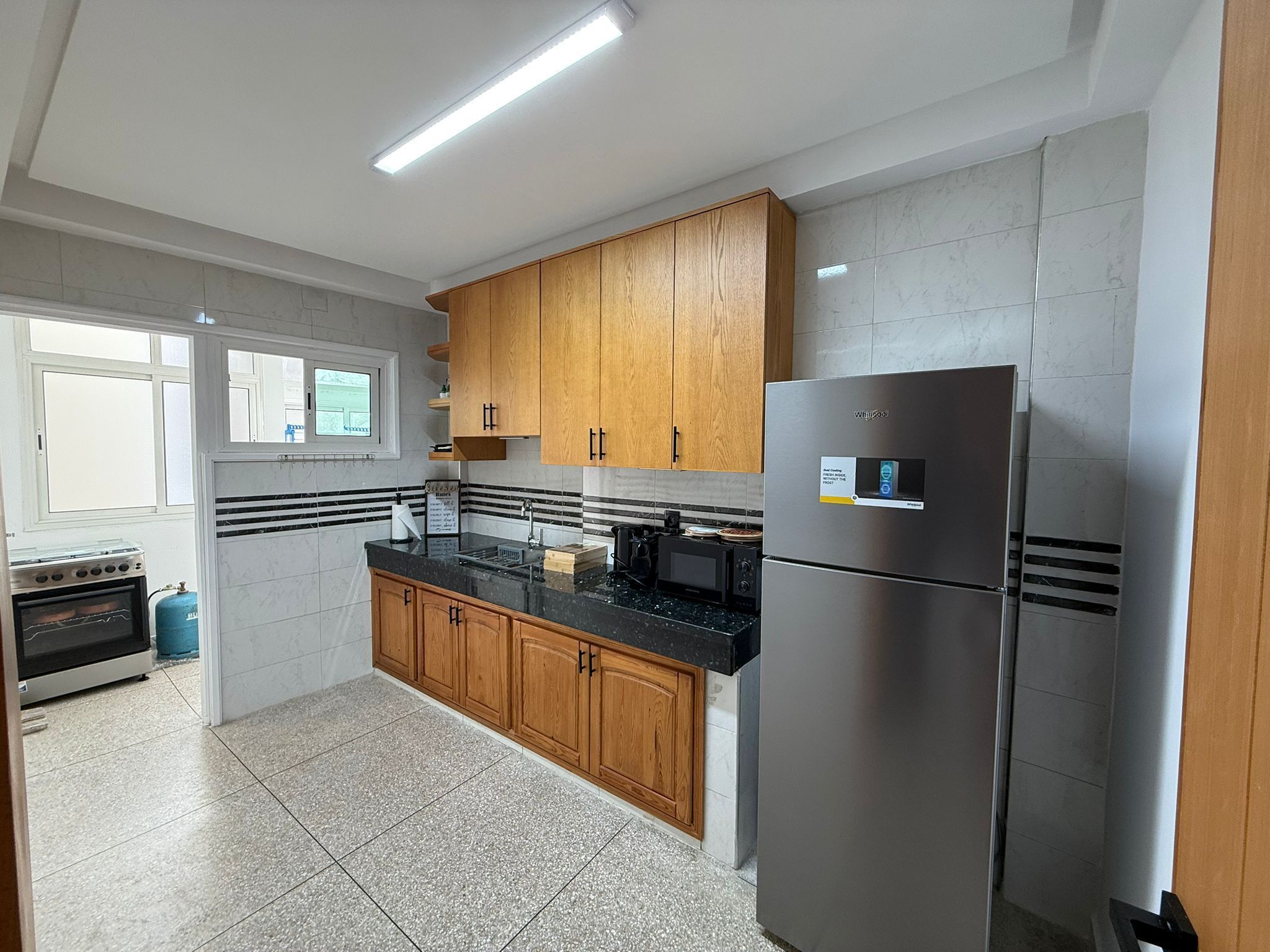 A modern kitchen with wooden cabinets, a stainless steel refrigerator, and a gas stove.
