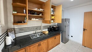 Une cuisine moderne avec des meubles en bois, un plan de travail en granit noir et un réfrigérateur en acier inoxydable.
