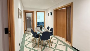 Un espace repas moderne avec un sol à carreaux, une table rectangulaire et quatre chaises.