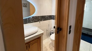 Une salle de bain moderne avec un lavabo en marbre, des toilettes et une douche.