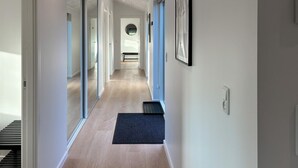 Un pasillo moderno con piso de madera, puertas de vidrio y felpudo negro.