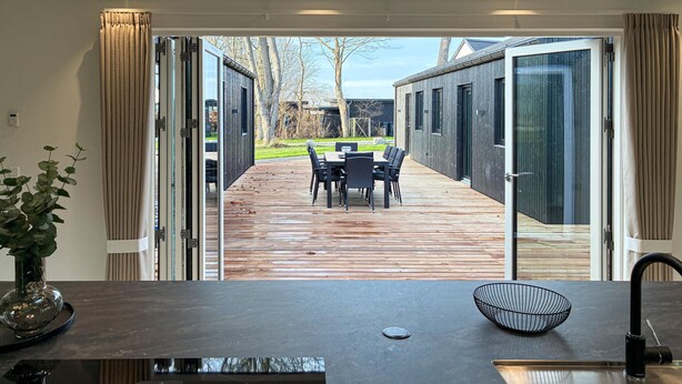 Una cocina moderna con una terraza de madera que da a un comedor al aire libre.