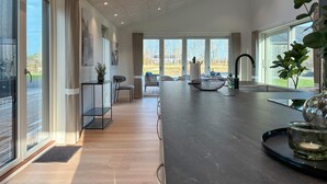 Una cocina moderna con encimera oscura, ventanas amplias y vistas al exterior.