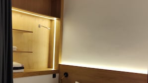 Ein ordentlich bezogenes Bett mit weißen Leinen, einem Holzkopfschild und einer Nachttischlampe.
