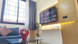 Ein modernes Wohnzimmer mit flachbildfernseher an der Wand, einer Couch, einem Couchtisch und einer Topfpflanze.