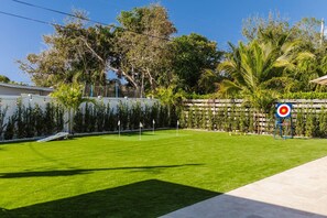 A well-maintained golf course with a clear target area, surrounded by lush greenery and a white fence.