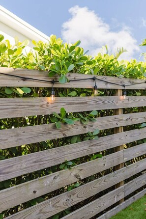 A wooden fence with climbing plants and string lights.