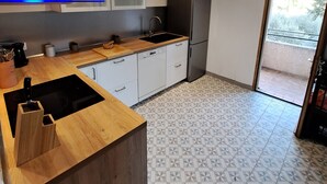 A modern kitchen with a wooden countertop, built-in appliances, and patterned floor tiles.