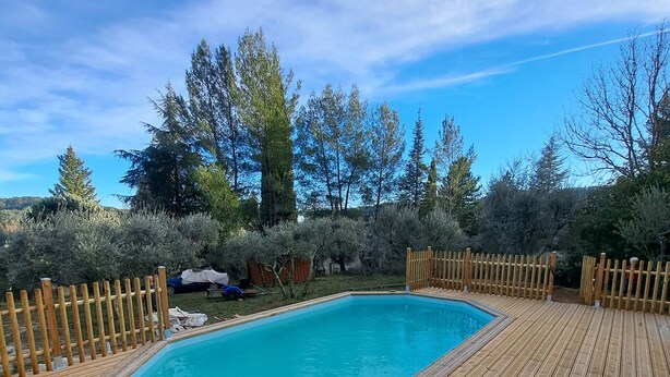A wooden deck surrounding a rectangular swimming pool with a clear blue sky above.