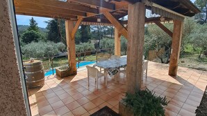 A covered patio with a pool, wooden pergola, and tiled flooring.