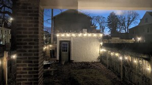 A covered outdoor area with a brick wall, a door, and a small table.