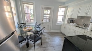 A kitchen with white cabinets, a glass dining table, and a black stove.