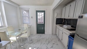 A compact kitchen with white cabinets, a green door, and a marble floor.