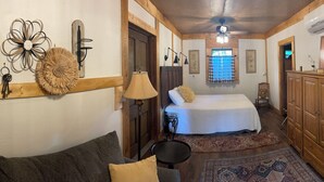 A narrow hallway leading to a bedroom with a bed, a wooden wardrobe, and a small table.