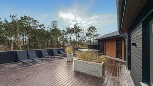 Een houten terras met buitenmeubels en een plantenbak.