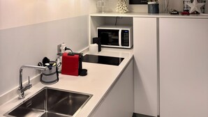 Una cuina moderna amb microones integrat, rentamicrodats d'acer inoxidable i il·luminació penjant.