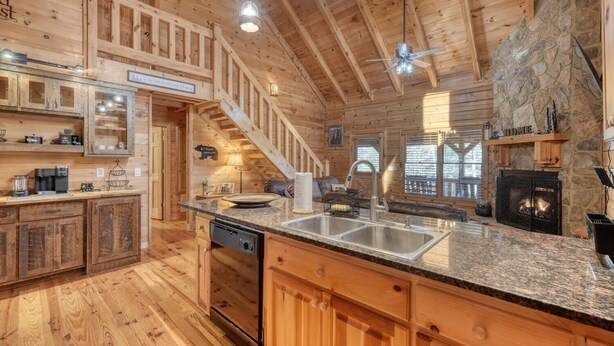 A spacious kitchen with granite countertops, a dishwasher, and a stone fireplace. - Black Bear Ridge (Blairsville)