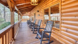 A wooden cabin with a porch, rocking chairs, and a hanging light fixture. - Black Bear Ridge (Blairsville)
