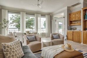 A spacious living room with a sofa, armchairs, a round coffee table, and a dining area with a table and chairs.