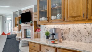 A modern kitchen with wooden cabinets, a marble countertop, and a built-in coffee maker. - Stunning Views, Open Water, Hot Tub, 5 BR, 4 BA (Granbury)